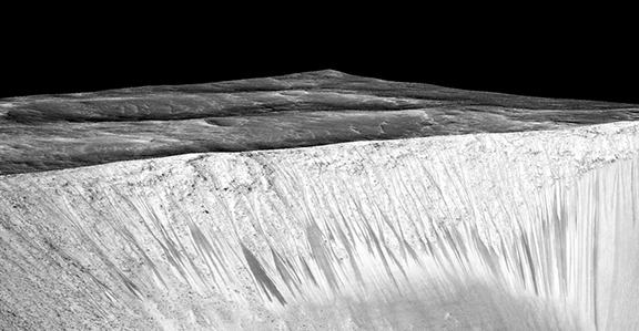 Dark narrow streaks called recurring slope lineae emanating out of the walls of Garni crater on Mars (Photo by NASA)