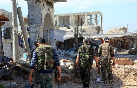 Pro-government fighters walk past debris in the Syrian town of Arbid on the outskirts of Kweyris military airbase, in the northern Syrian province of Aleppo, on November 12, 2015 (Source: AFP PHOTO / George Ourfalian)