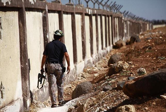 A Free Syrian Army fighter carries his weapon as he walks along the fence of the Menagh airport. 2013. (Source: Reuters/Hamid Khatib)