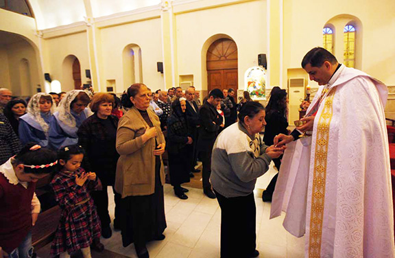 A priest gives communion to an Iraqi Christian woman, during mass at Mar George Chaldean Church in Baghdad, March 1, 2015  (Reuters photo)