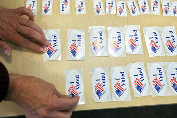 An election worker lays out "I Voted" stickers for voters 