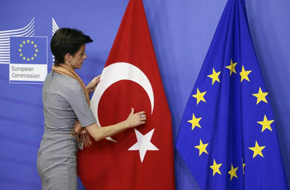A woman adjusts the Turkish flag next to the European Union flag at the EU Commission headquarters in Brussels (Photo: Reuters/Francois Lenoir)