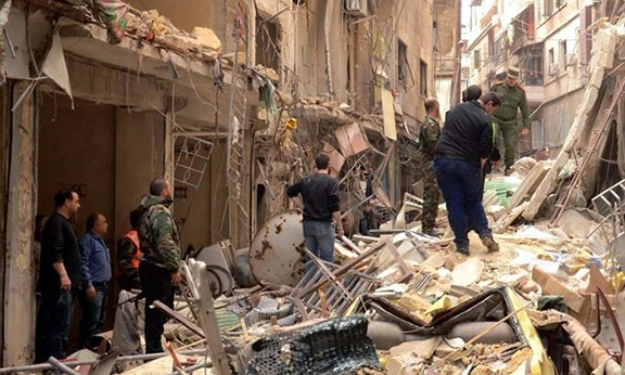 Syrians walk through the rubble following reported rocket attacks by rebel fighters in northern Aleppo. (Photo: George Ourfalian/AFP/Getty Images)